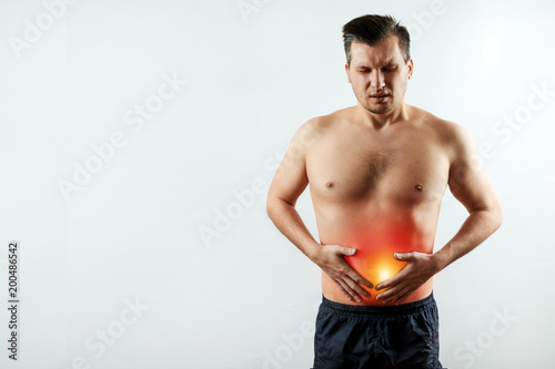 Fotografie, Obraz Front view, the man holds his hands to the stomach, abdominal pain, pain in the stomach highlighted in red