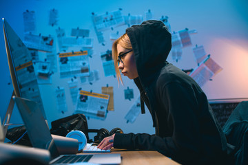 Wall Mural - side view of female hacker developing malware in dark room