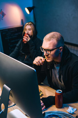 Wall Mural - young hackers drinking beer and eating junk food while working on malware