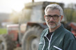 © goodluz - Farmer standing by tractor outside the barn