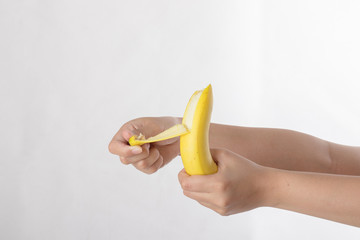 Hands hold and peel banana isolated on white background.