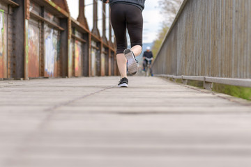 Wall Mural - Sporty woman running on an old boardwalk bridge