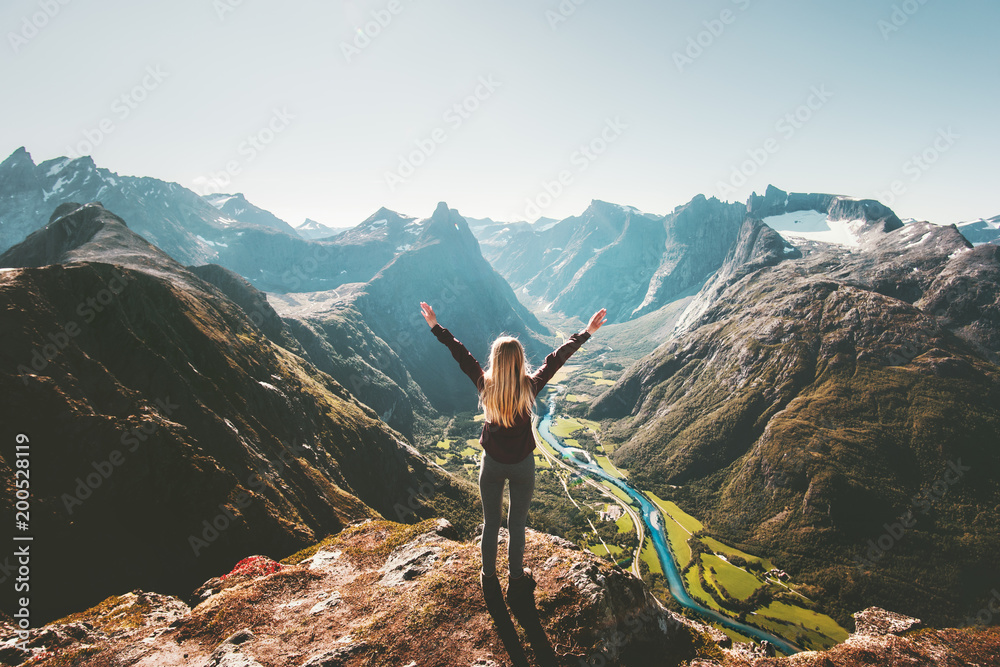 Woman traveler raised arms standing alone on cliff in mountains landscape Travel healthy Lifestyle adventure active vacations getaway in Norway - obrazy, fototapety, plakaty 