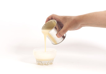 Male hand pouring condensed milk into a bowl