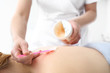 Olejek do masażu. Kosmetyczka nakłada preparat kosmetyczny na plecy kobiety