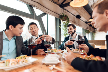 Meeting with chinese businessmen in restaurant. Men are drinking wine.