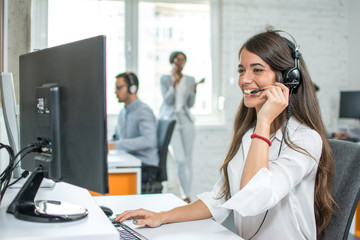 Wall Mural - Young friendly operator woman agent with headsets working in a call centre.