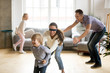 © fizkes - Blindfolded mother catching little son playing hide and seek at home, happy children having fun with mom and dad, parents with kids spending time together in living room, weekend family games concept