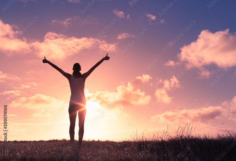Young woman raising her arms up against the sunset feeling free. Happiness and joy concept. - obrazy, fototapety, plakaty 