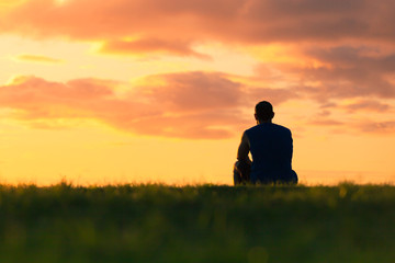 man sitting alone watching the beautiful sunset.