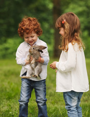 Canvas Print - boy and girl playing with rabbit in park