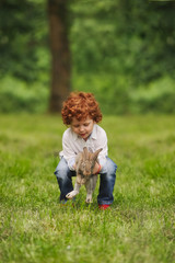 Canvas Print - litle boy plays with rabbit in park