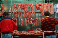 Men Working In A Hong Kong Meat Market. Meat Cutters In An Open Air Market In The Central District Of Downtown Hong Kong Displaying A Variety Of Cuts Of Meat Items.