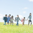 © amanaimages - 草原で手をつなぐ小学生と先生