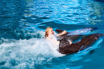 Wall Mural - Happy child and dolphins in blue water. Dolphin Assisted Therapy