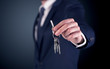 © ra2 studio - Young businessman hand over keys with empty dark background