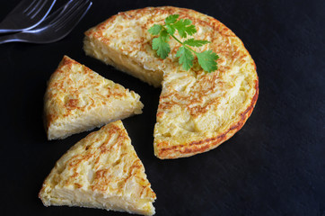 Homemade tortilla,  typical Spanish omelette made with eggs and potatoes.  Spanish tapas or snack served in black board