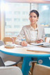 © pressmaster - Young confident businesswoman organizing her work while working by table in cafe