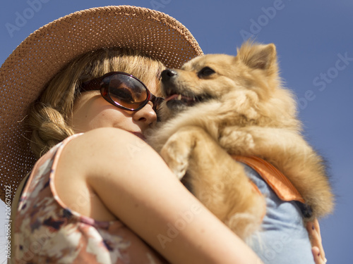 Fotografie, Obraz Retrato modelo blanca y rubia, con pamela y gafas de sol, abrazando a su perrito cariñosamente