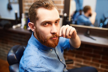 Young handsome bearded man visiting barber shop. Barber concept.