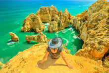 Tourism In Algarve. Summer Holidays In Portugal, Europe. Lifestyle Tourist Sitting On Promontory Of Ponta Da Piedade. Caucasian Woman Looking Amazing Views Of Iconic Cliffs Of Turquoise Sea Of Lagos.