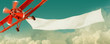 Leinwandbild Motiv Vintage red airplane flying in the sky with a white blank banner