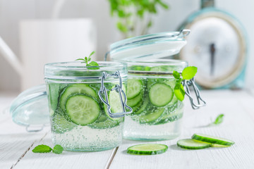 Wall Mural - Refreshing water in jar with cucumber on white table