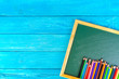 Close up arrangement of pencil color and chalk board on blue background. Preschool, education, back to school and copy-space concept or other your content.