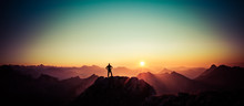 Man Reaching Summit Enjoying Freedom And Looking Towards Mountains Sunrise.