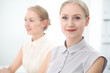 © rogerphoto - Two business ladies or colleagues discussing something in office background