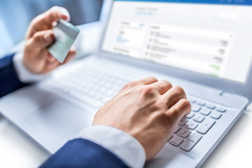 Man hands typing on the keyboard of laptop holding credit card, close-up of online shopping