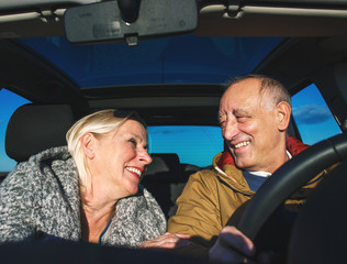 Portrait of smiling elderly couple driving car.