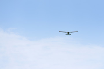 Light propeller aircraft comes to land on a blue sky background