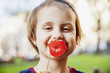 Cute little child girl holding fake paper smile in front of lips.