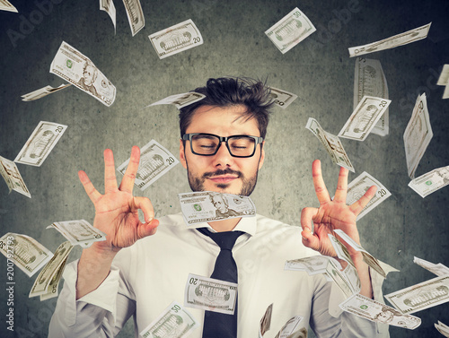 Fotografía Business man meditating under money rain