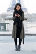 © nenetus - Smiling asian young woman using her mobile phone in front of Eiffel tower.