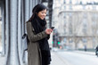 © nenetus - Smiling asian young woman using her mobile phone in the street.
