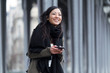© nenetus - Smiling asian young woman using her mobile phone in the street.