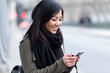 © nenetus - Smiling asian young woman using her mobile phone in the street.