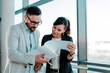 © bnenin - Two business colleagues looking at documents in bright office interior.
