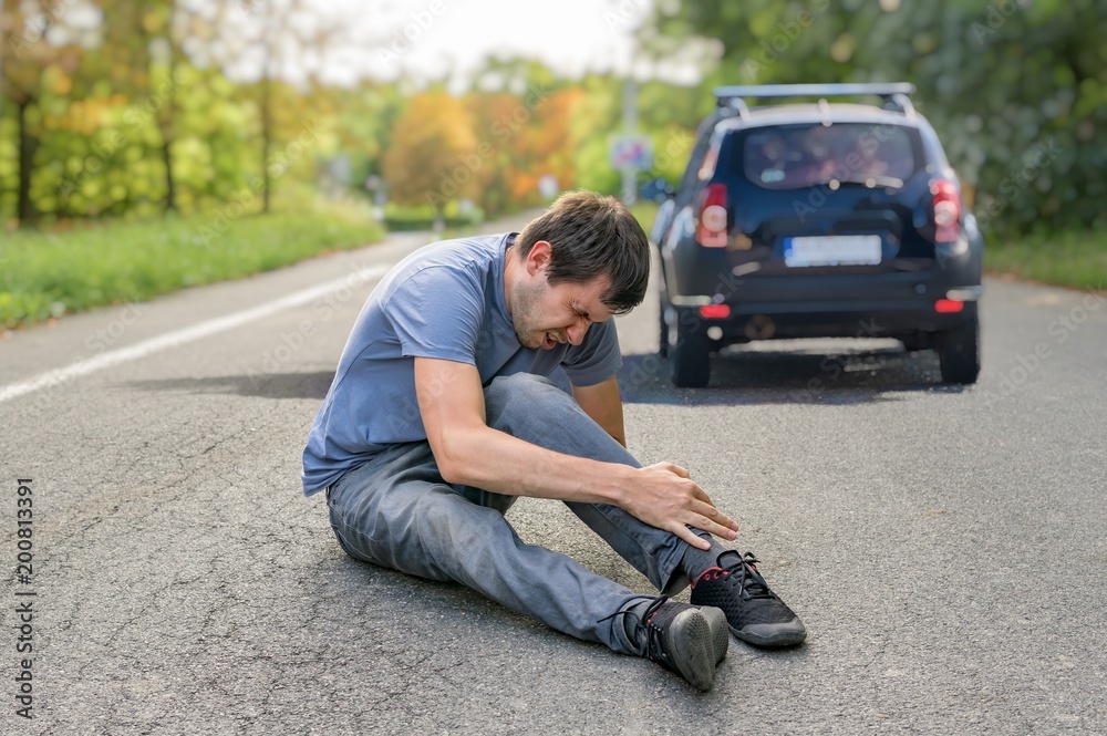 Hit and run concept. Injured man on road in front of a car. Stock Photo ...