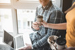 © Yakobchuk Olena - Woman extending hand with drink to male colleague. Man sitting with laptop and taking cup