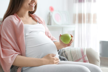 Wall Mural - Young pregnant woman holding apple at home
