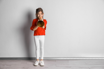 Wall Mural - Adorable little girl with vintage megaphone near light wall