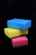 © Inga - Stack of three colorful sponges for washing dishes on black background.