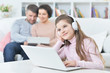 © aletia2011 - Happy girl  sitting at table with laptop with her parents on bac