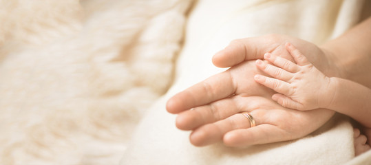 Wall Mural - female hand holding her newborn baby's hand. mom with her child. maternity, family, birth concept. c