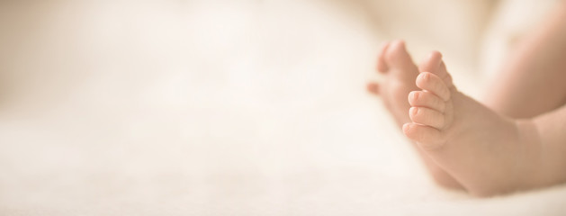 Wall Mural - newborn baby feet on creamy blanket. mom and her child. maternity, family, birth concept. copy space