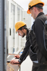 Wall Mural - field service engineers inspect relay protection system with laptop computer