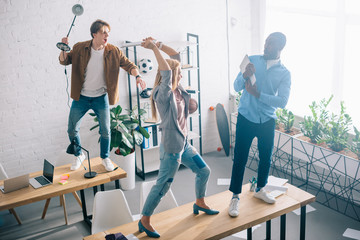 high angle view of two coworkers fighting with african american businessman with laptop in hands in modern office